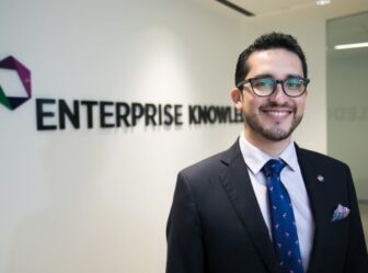 Guillermo Galdamez smiles at the camera while standing in front of the Enterprise Knowledge logo.