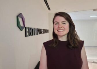 Nina Spoelker smiles at the camera while standing in front of the Enterprise Knowledge logo.